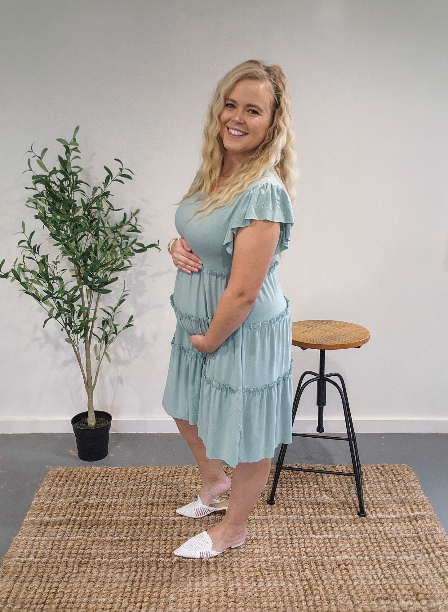 Side view of the ruffle sleeve tiered dress in dusty green showing it is bump friendly